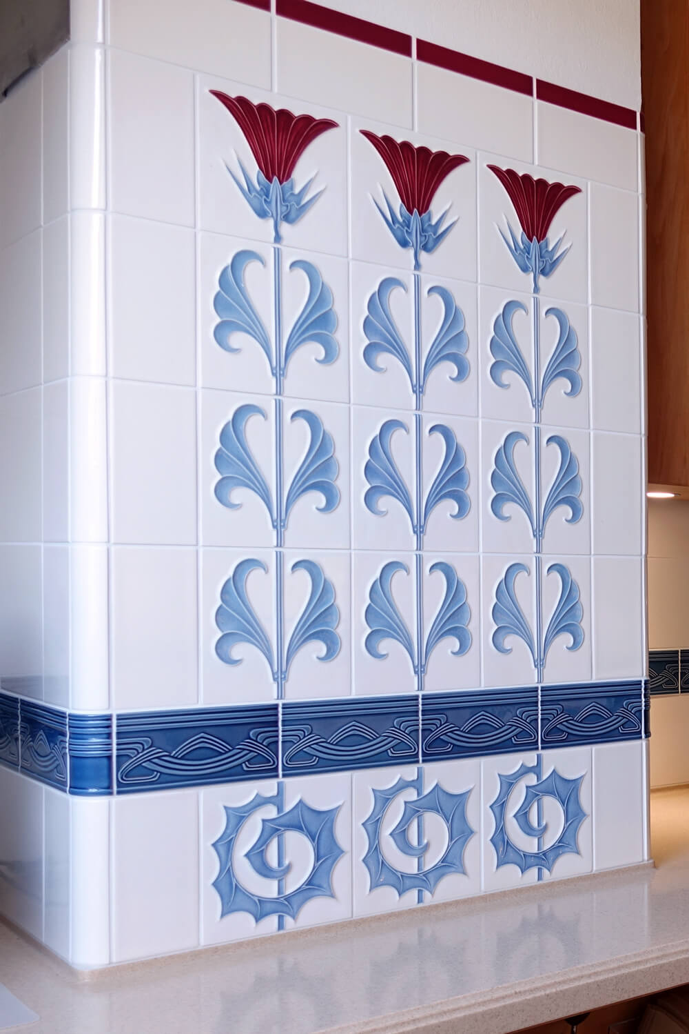 Küche mit Jugendstilfliese und Jugendstilbordüre von GOLEM. Florales Ornament in rot, weiß und blau. Entwurf: Tonwerke Offstein 1900